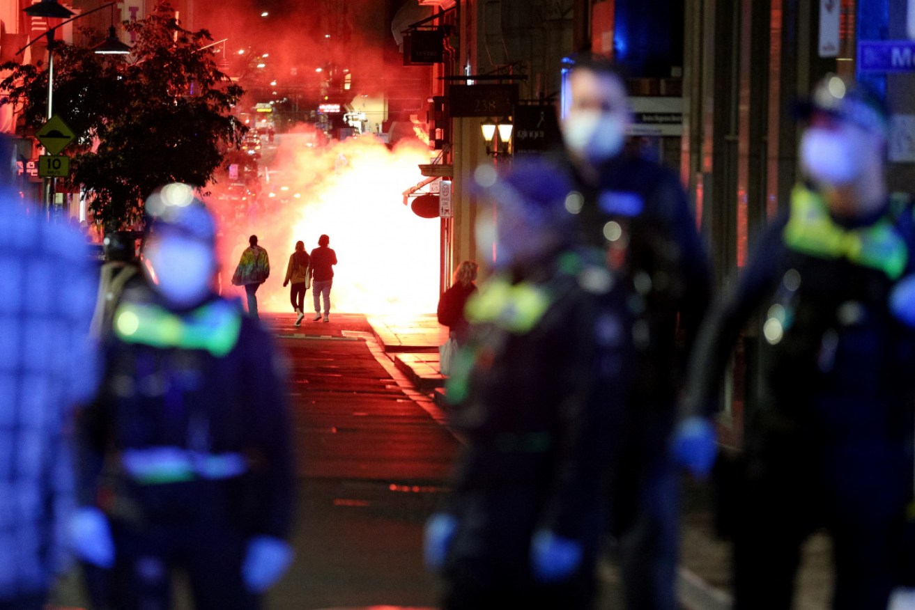 A flare is lit during lockdown protests in Melbourne on Thursday night.