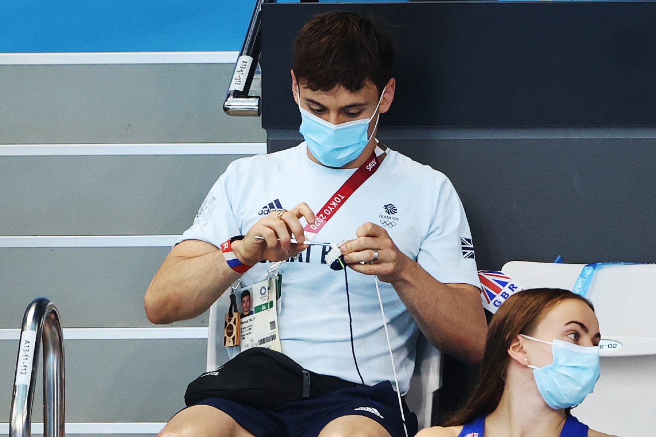 Daley works on his Team GB cardigan in the stands.