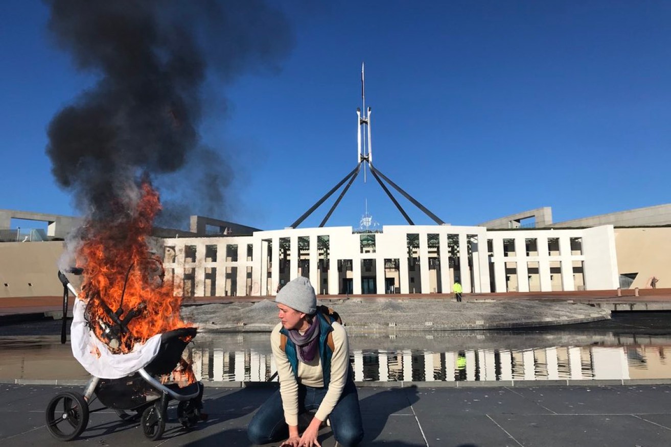 Climate protesters sprayed slogans and burned a pram outside Parliament House.