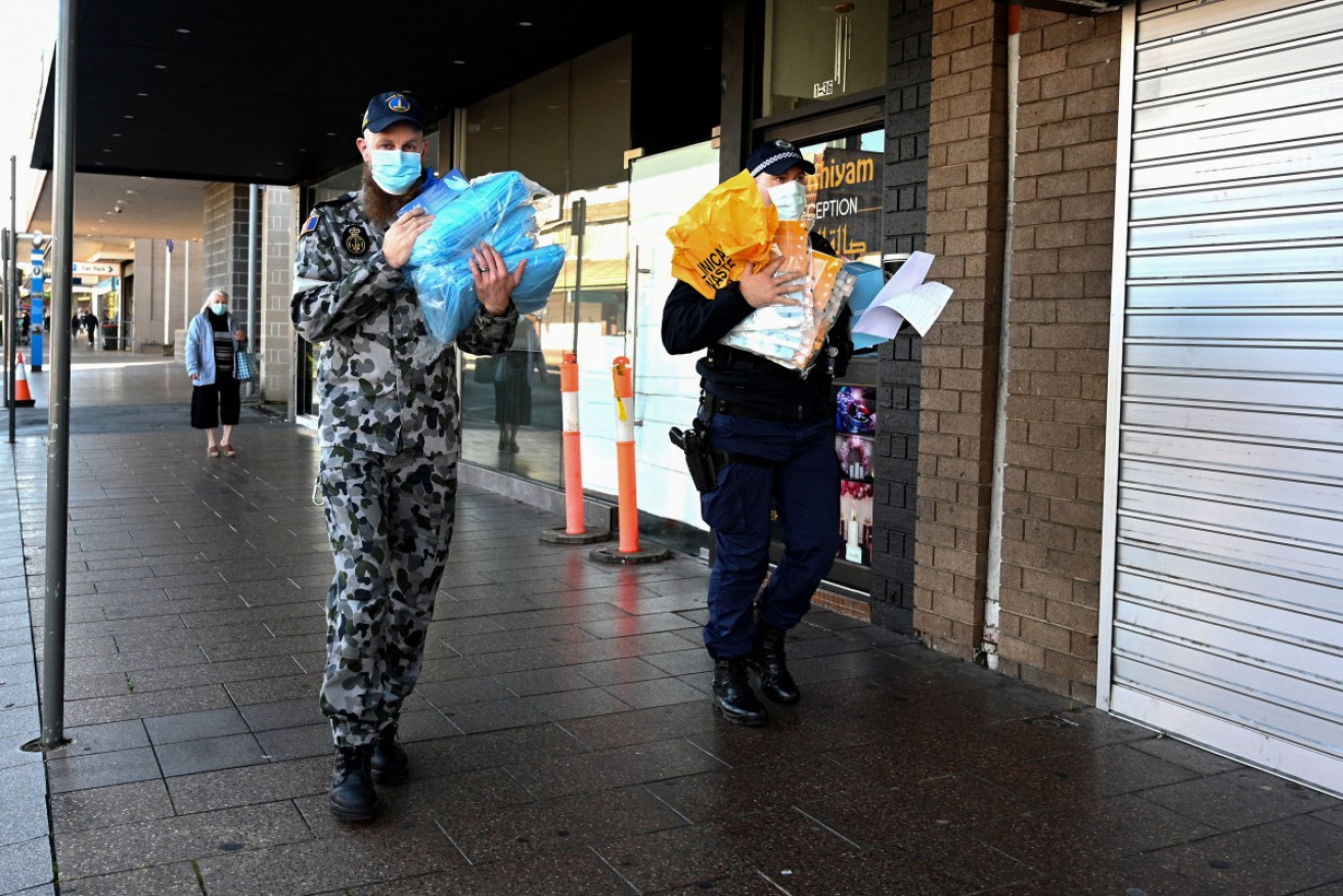 An ADF member and a police officer deliver protective equipment in Fairfield, in western Sydney.