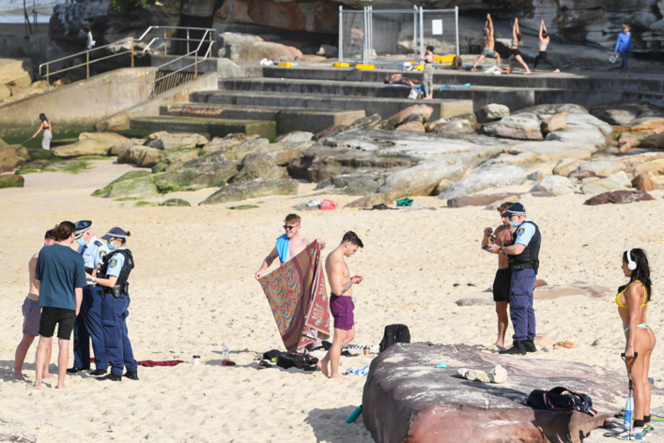 Police check the papers and identities of Bondi beachgoers on Saturday.