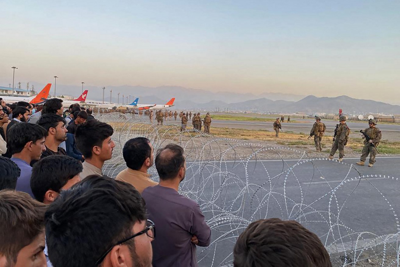 A crowd of Afghans at Kabul airport as US troops stand guard on Monday.