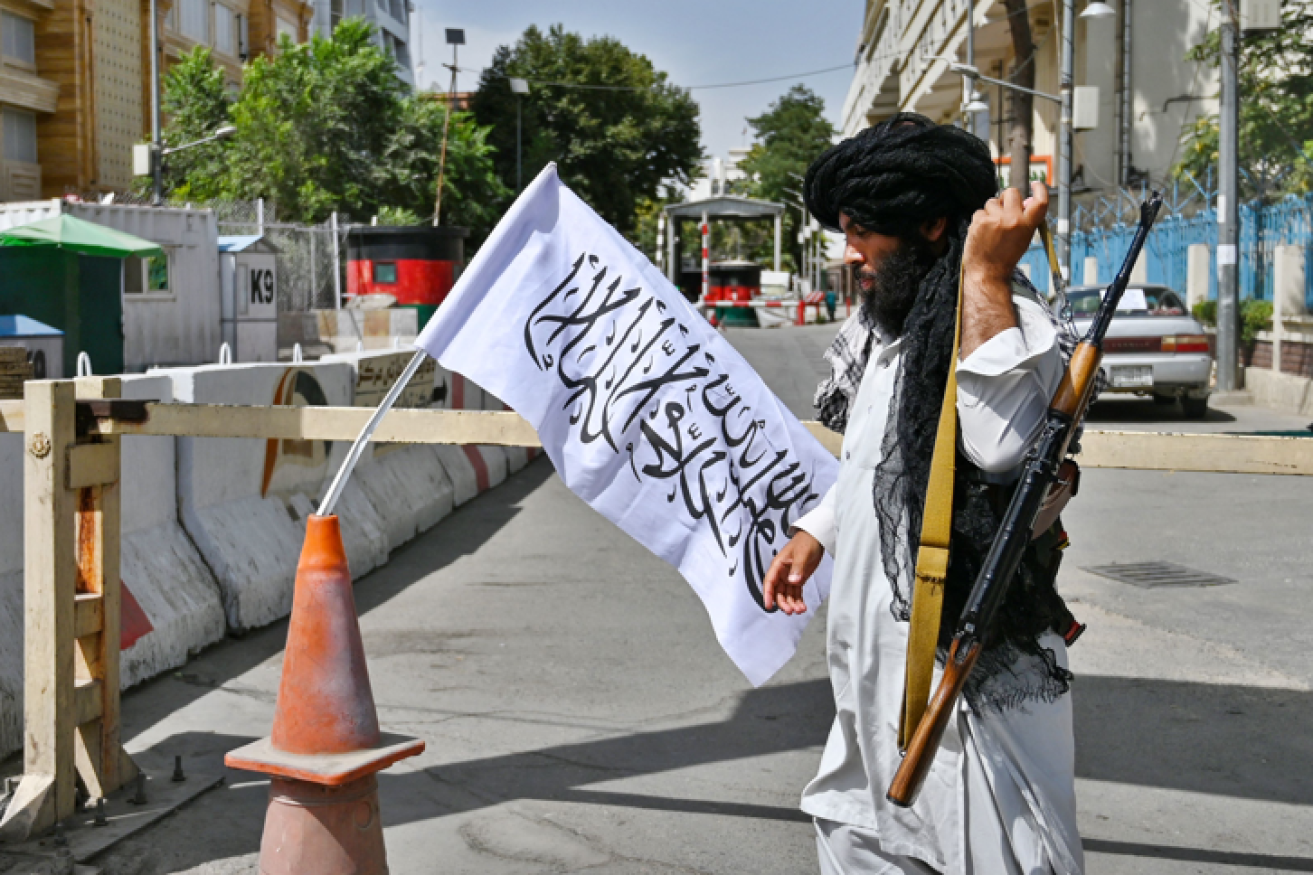 A Taliban militant mans a roadblock in the heart of Kabul as order and evacuation flights recommenced.