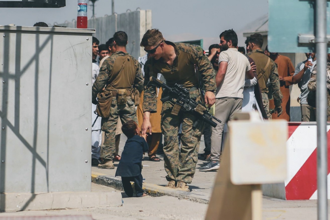 A photo provided by the US Marine Corps, shows a marine helping a child at Kabul's airport.