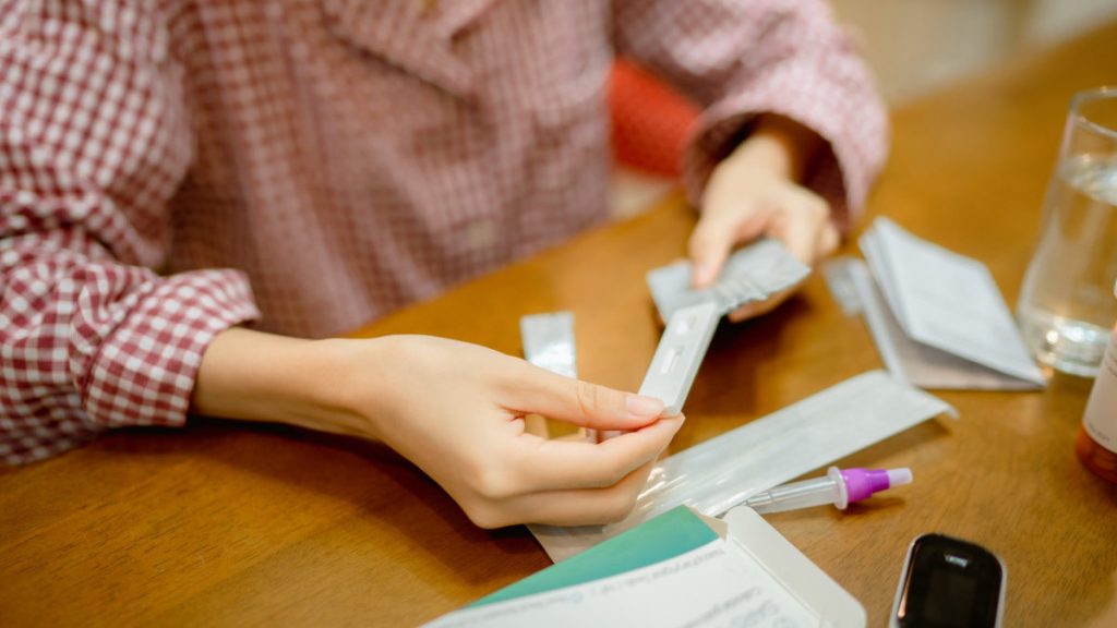Woman unpacking rapid antigen test kit at home