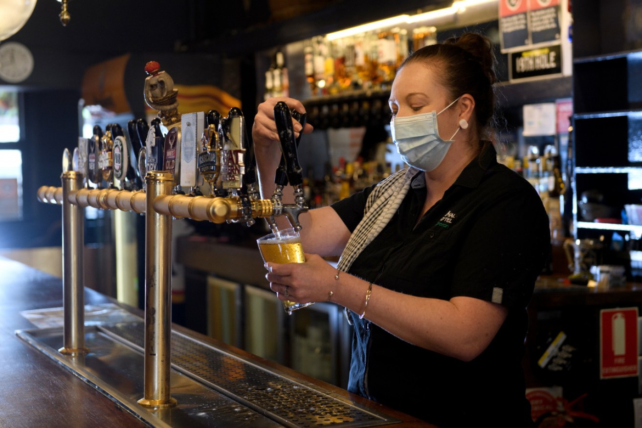 Royal Hotel Manager Amber Obernier runs the beer taps as she prepares to reopen in Oberon in the central Tablelands region of NSW. 