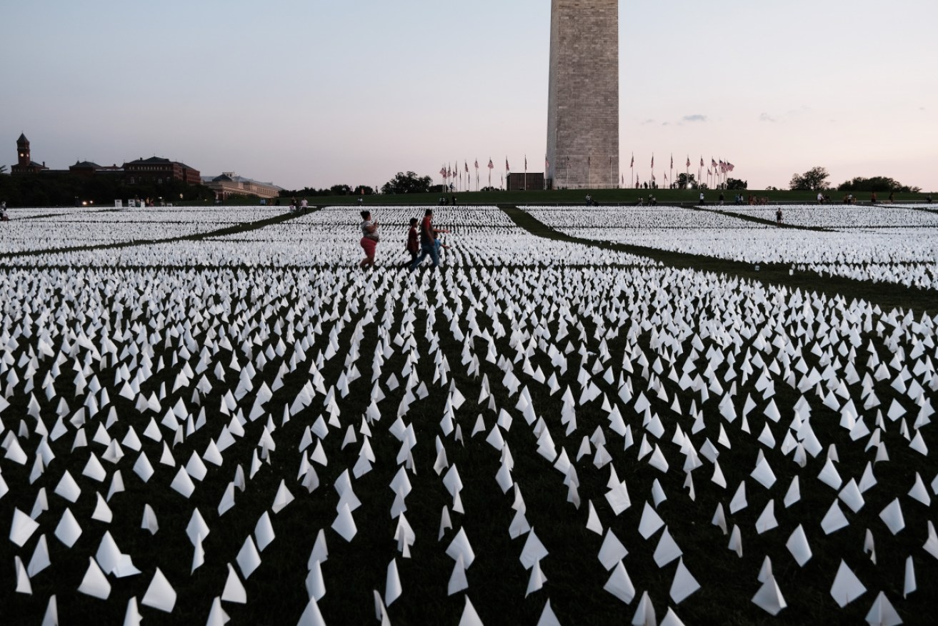 Visitors walk through a sea of flags on the grounds around the Washington Monument – one for every American dead of COVID.