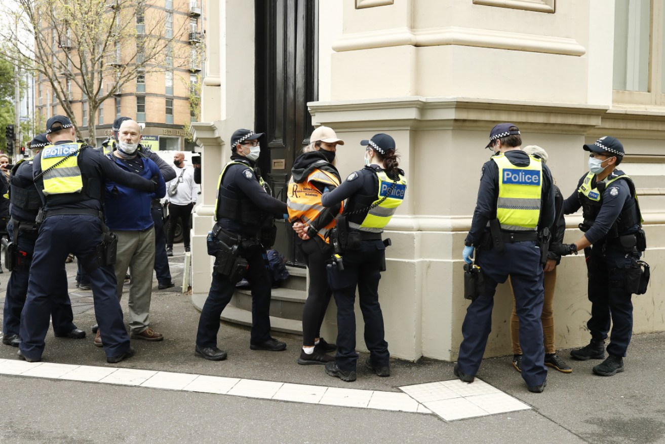 Victoria Police officers detain protesters near the CFMEU headquarters in Melbourne on Wednesday.