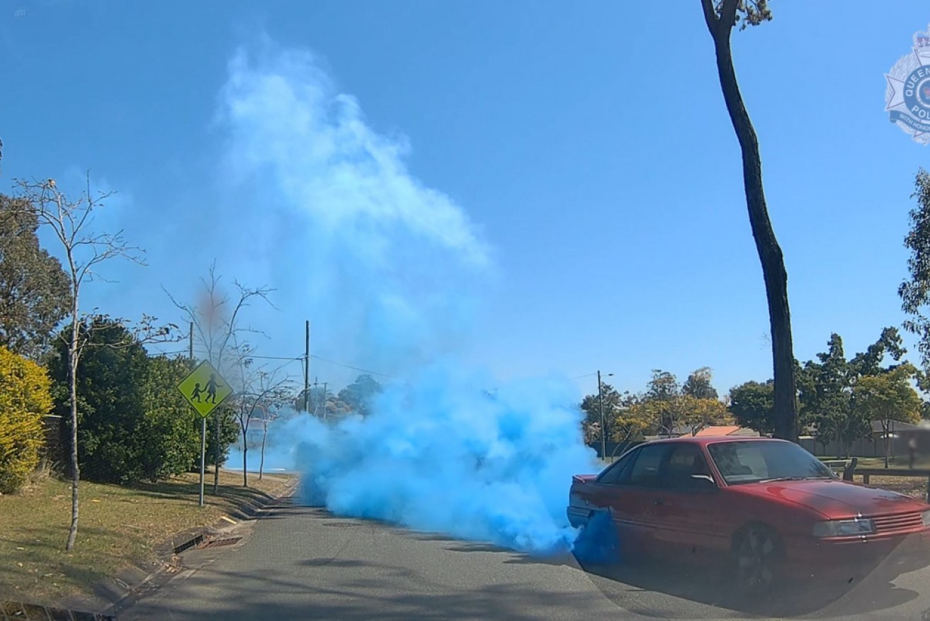 A man has been charged after hooning down a Queensland street doing burnouts and releasing blue smoke in a take on the gender reveal phenomenon.