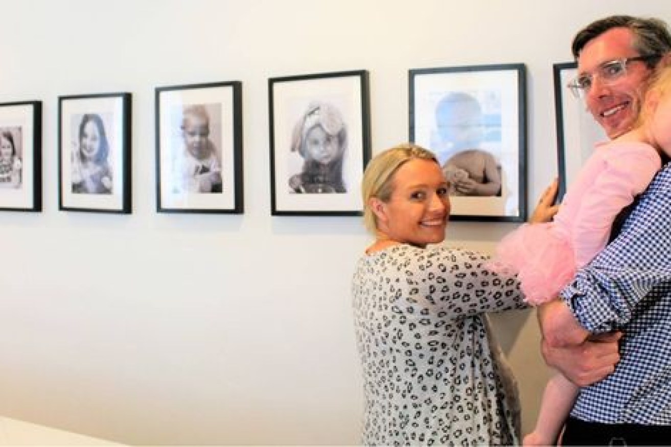 Dominic Perrottet and wife Helen and their wall of baby photos. 