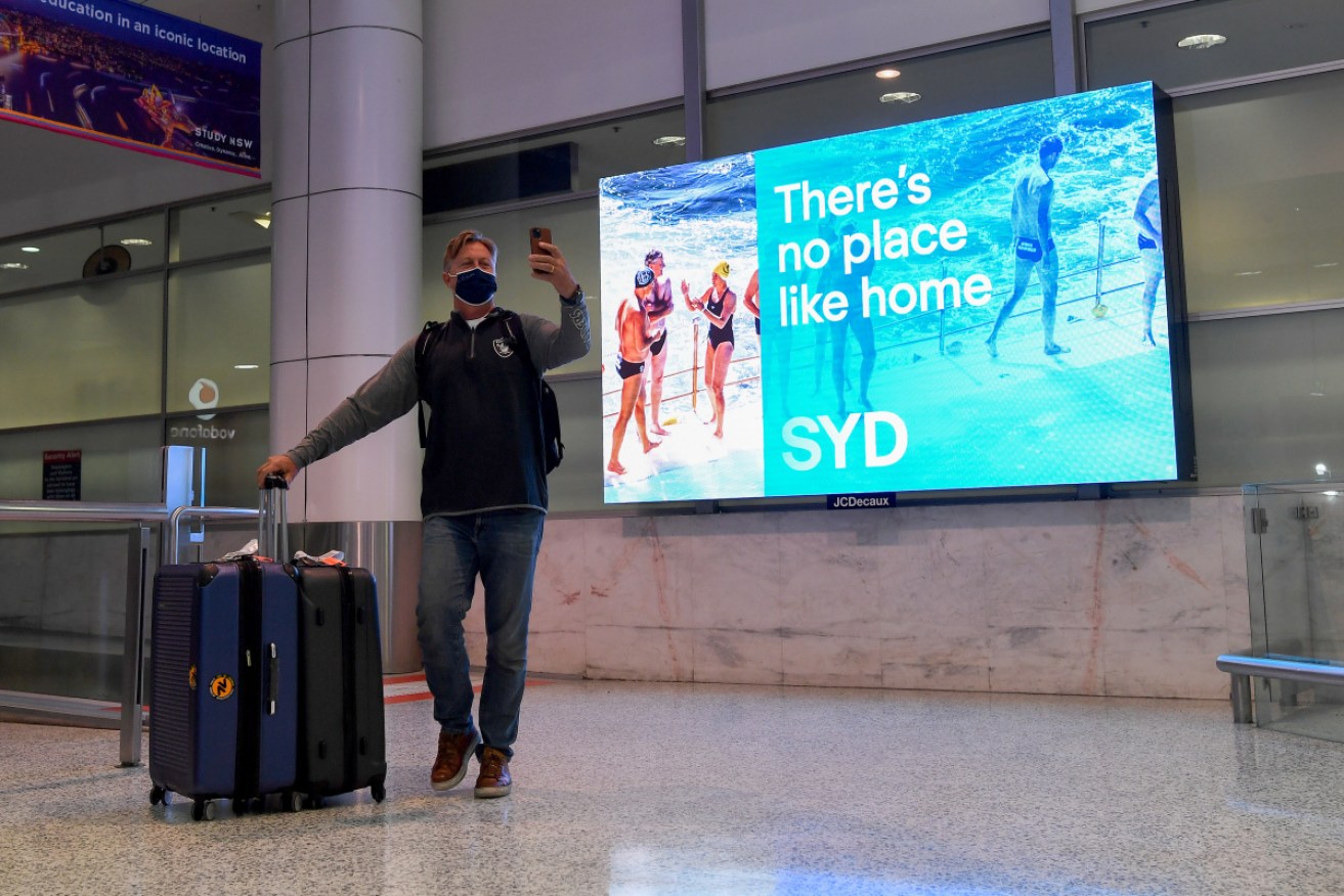 A returning traveller arriving on one of the first quarantine-free international flights takes a selfie at Sydney International Airport.