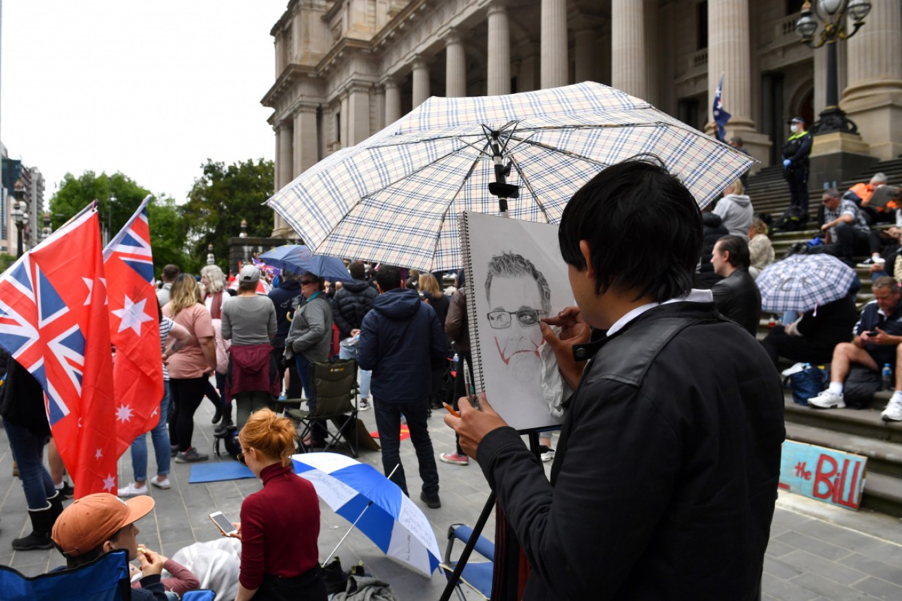 A man draws a portrait of Victorian Premier Daniel Andrews at the pandemic protest on the steps of state parliament.