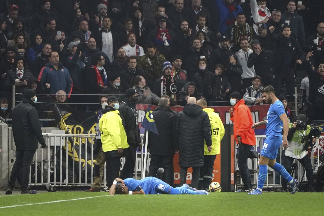 Marseille's Dimitri Payet lies on the ground after being hit by an object thrown by a Lyon fan.