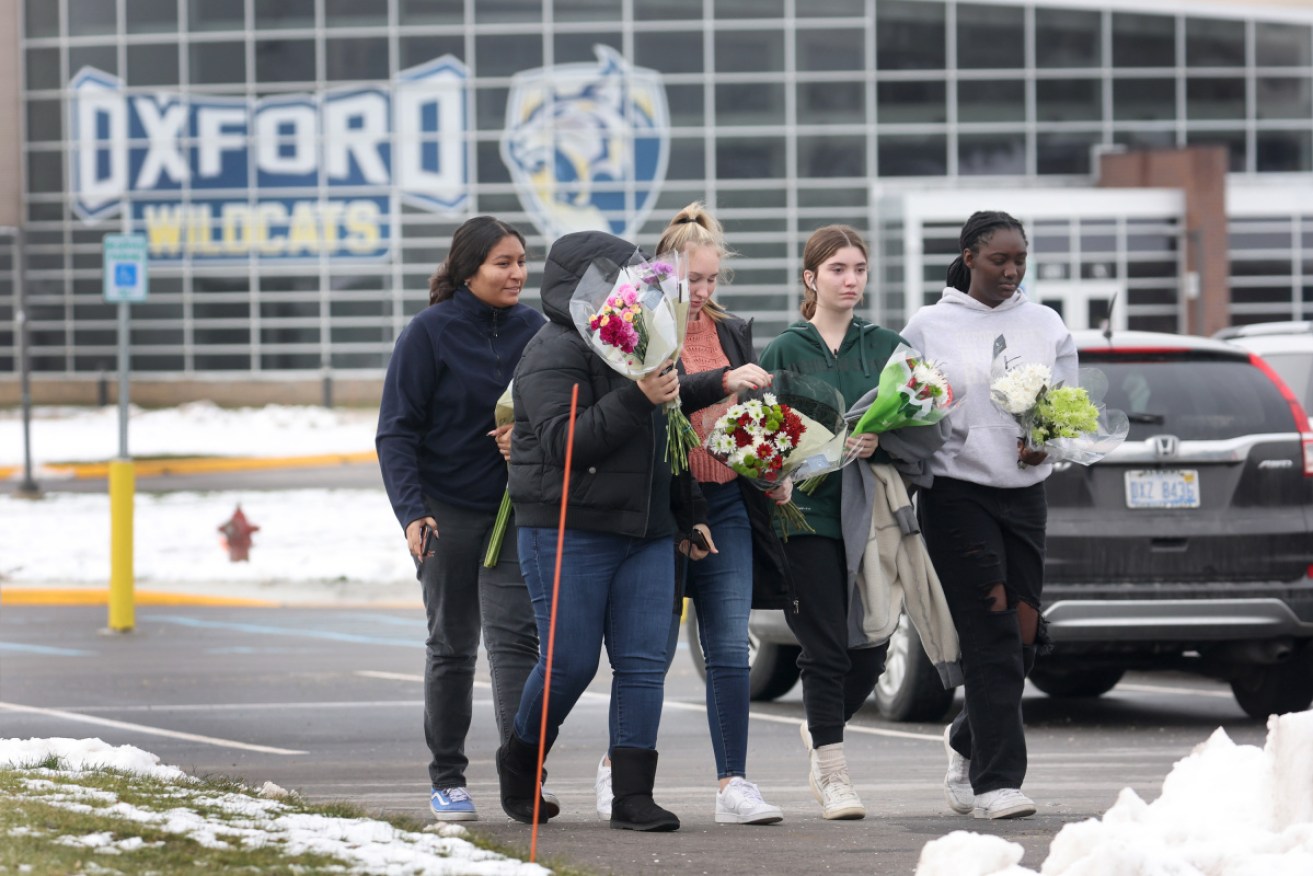 People bring flowers to a makeshift memorial outside the school, where four died in a shooting.