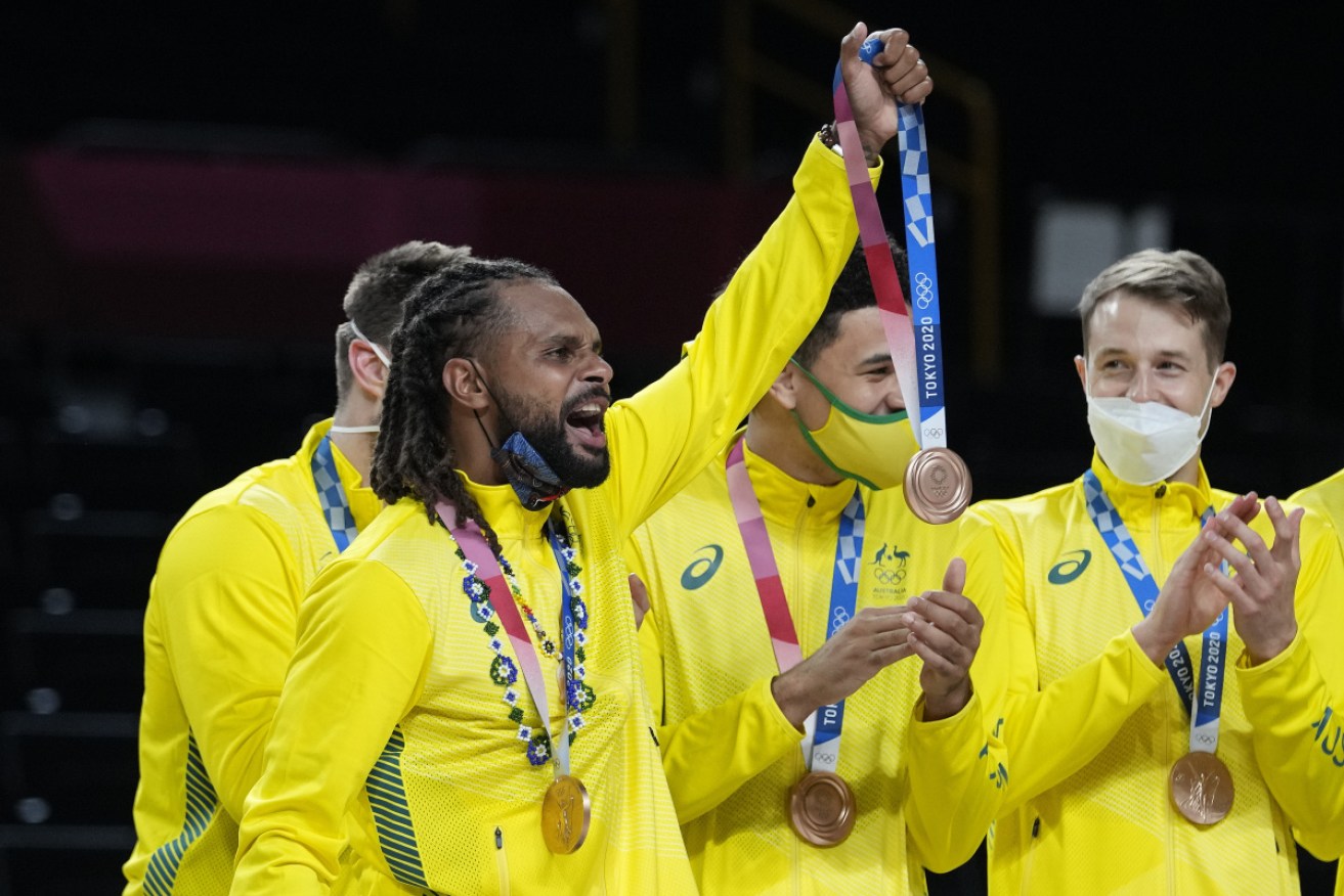 Patty Mills holds up his Olympic bronze medal .