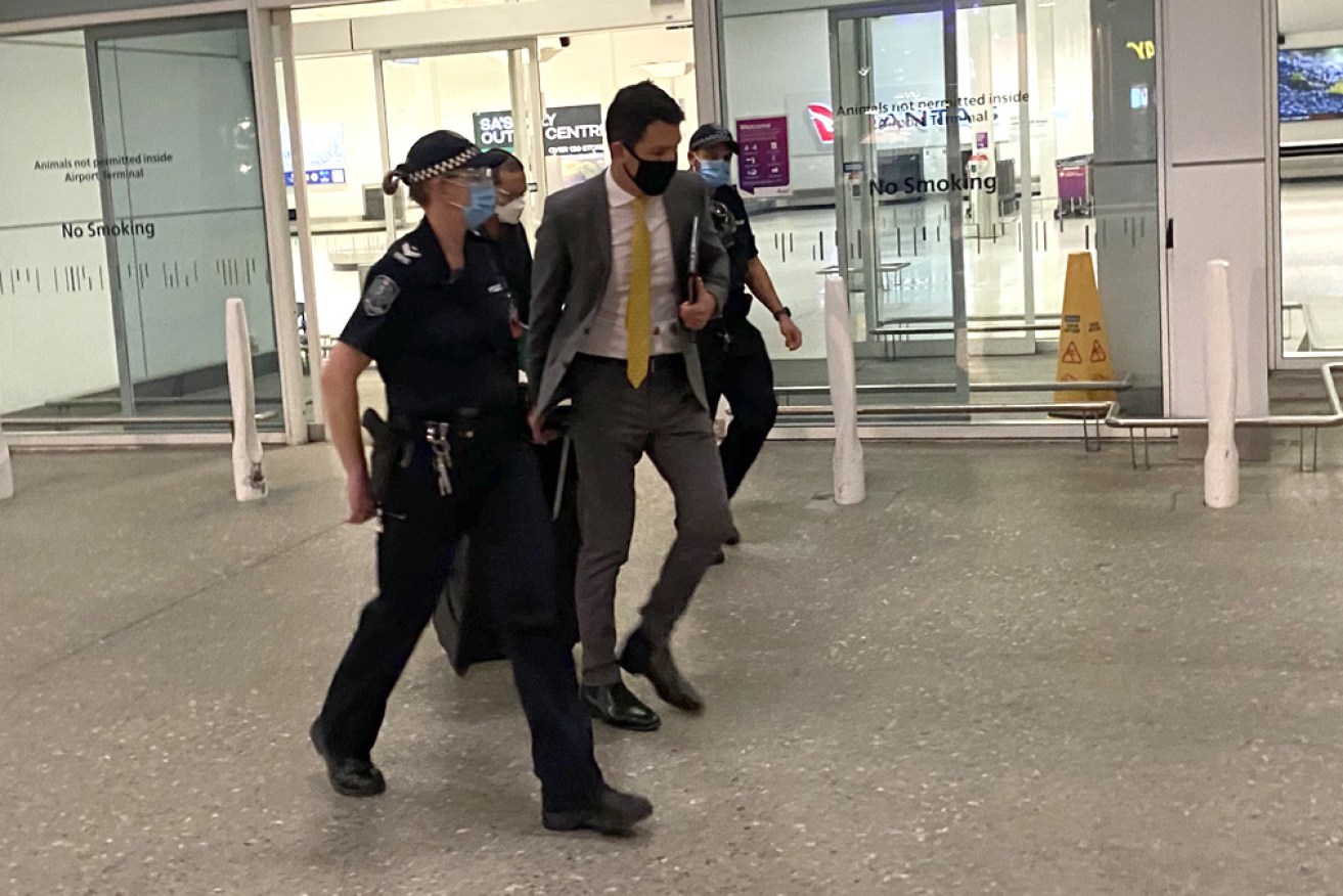 Senator Antic is escorted from Adelaide Airport on Thursday night. He is now in two weeks' quarantine.