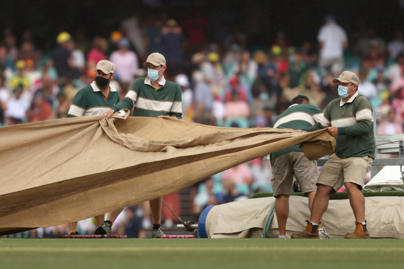 Ground staff cover the wicket as a shower disrupted play in the fourth Ashes Test at the SCG.
