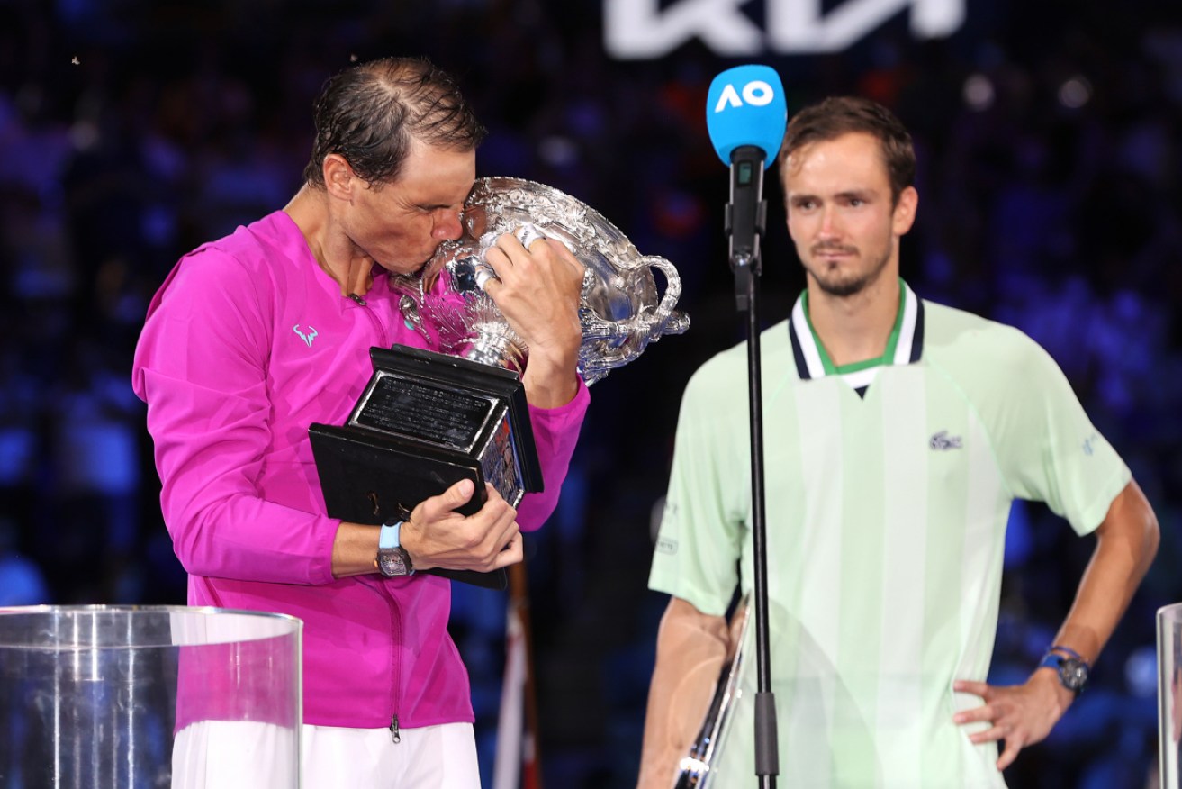 Rafael Nadal kisses the Norman Brookes Challenge Cup as Daniil Medvedev looks on after the Spaniard won the Australian Open men's singles final early on Monday morning.