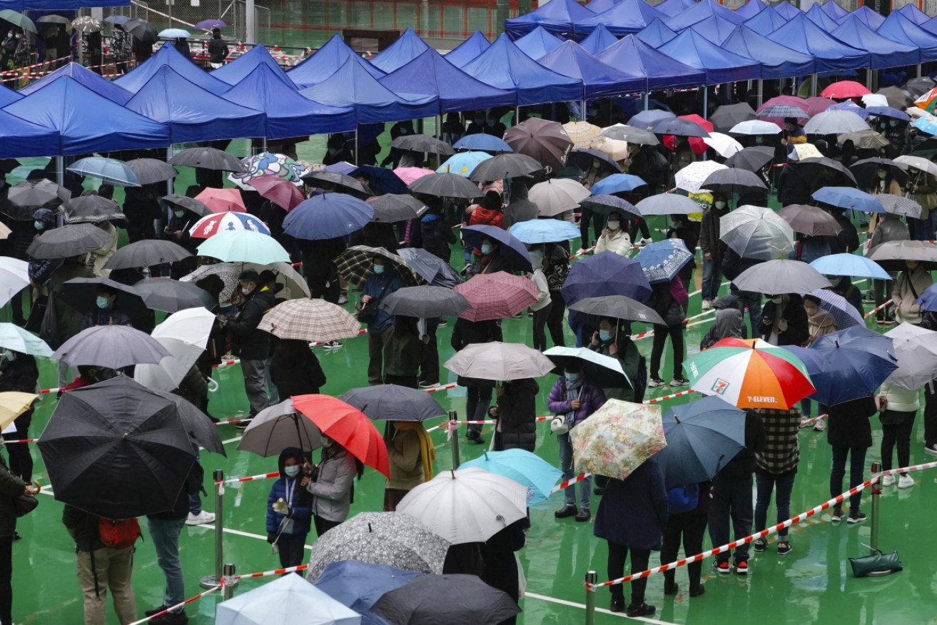 Hong Kongers brave the rain to line up for their tests and jabs.<i>Photo: AP</i>
