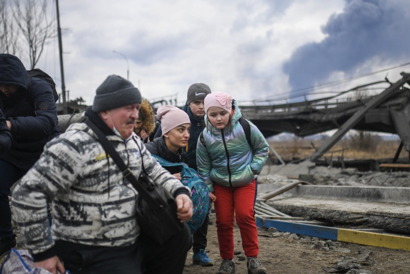 Ukrainian soldiers help civilians flee the battered city of Irpin, near Kyiv.