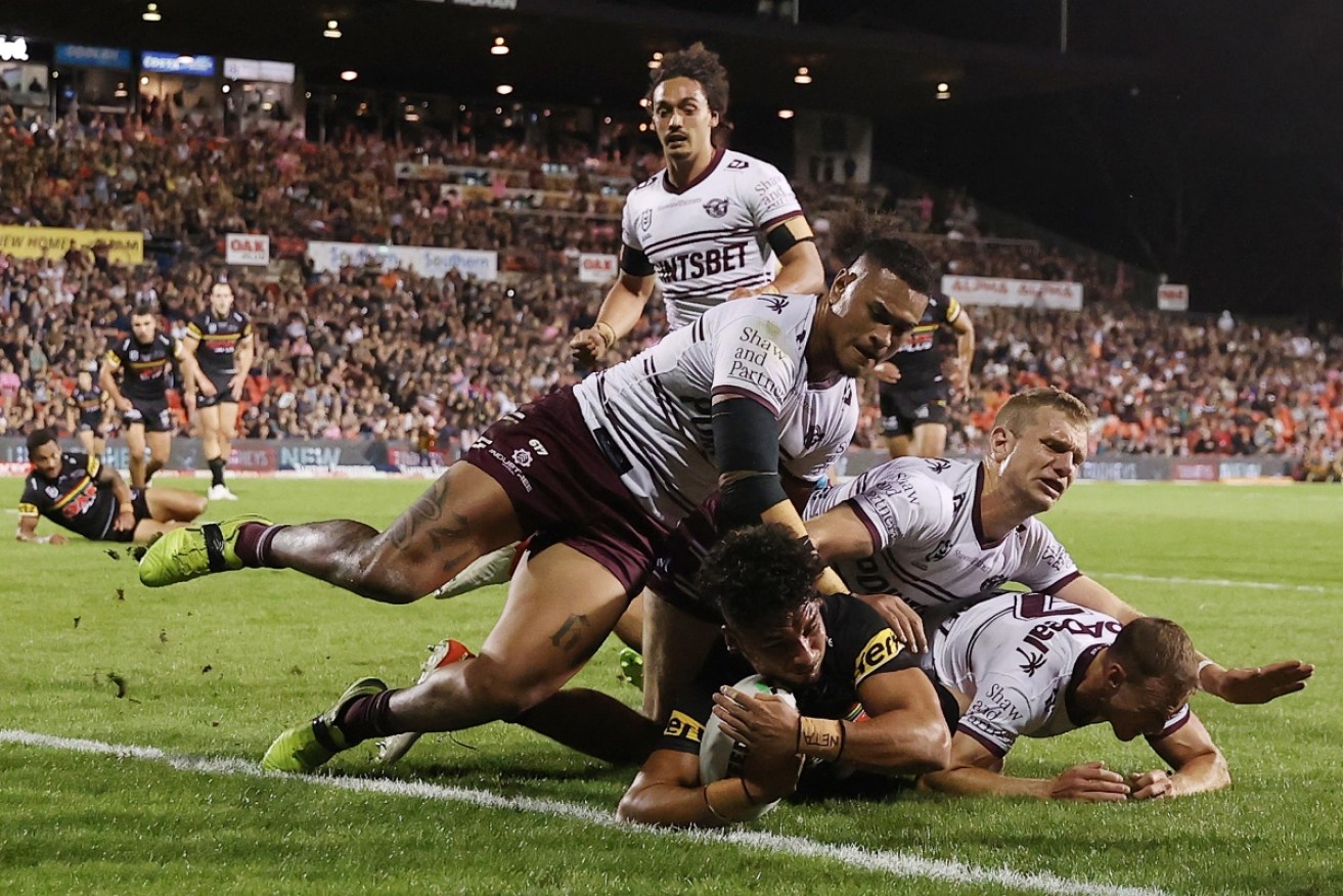 Penrith's Izack Tago  scores under a wall of Manly players  on Thursday night. 