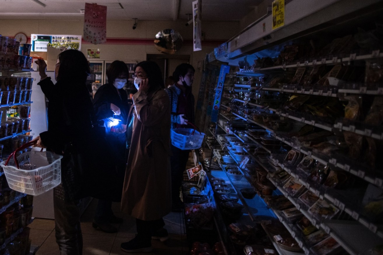 Tokyo residents shop in the dark after Wednesday's late-night quake cut power to millions of people.
