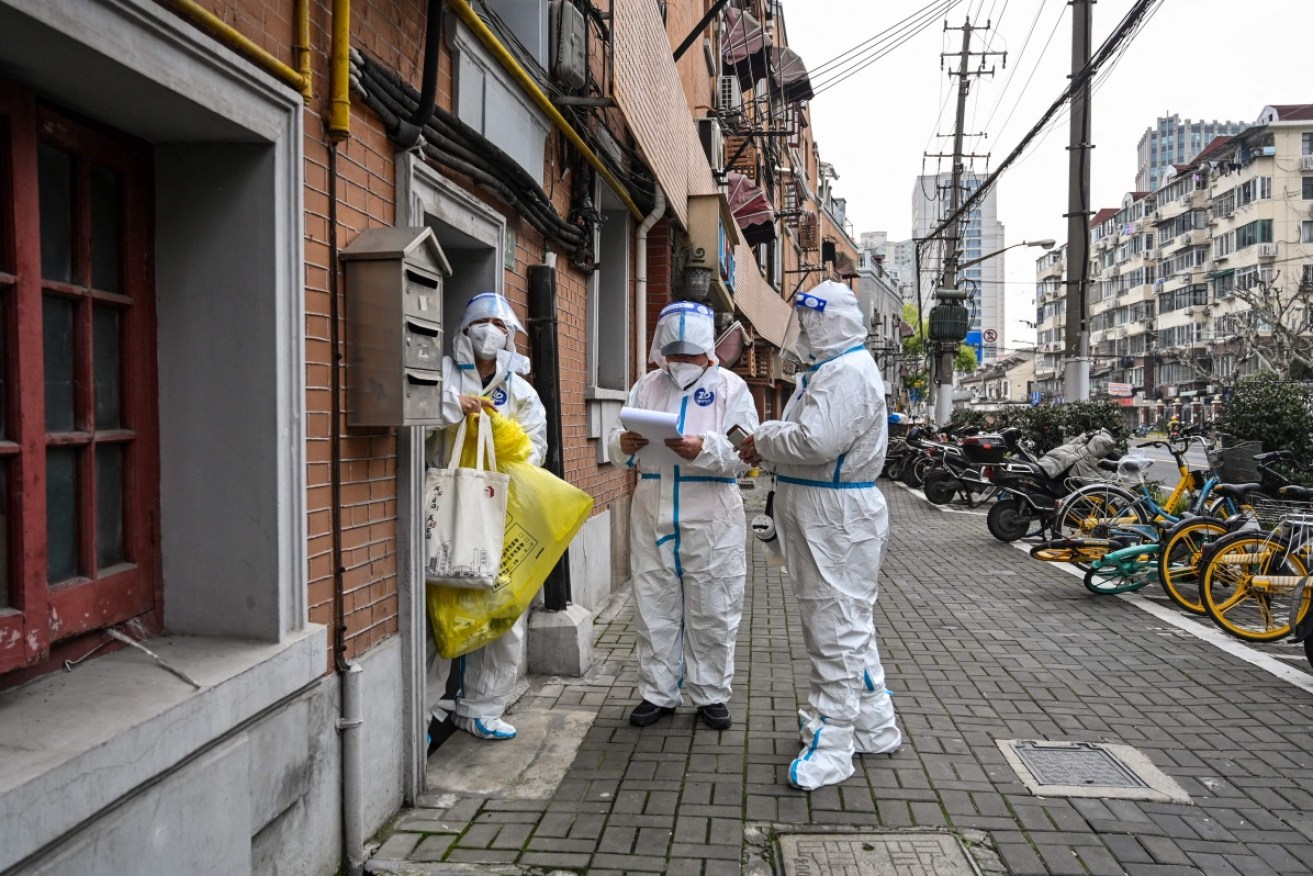 Health workers in protective gear enforce lockdown rules on a Shanghai street. <i>Photo: Getty</i>