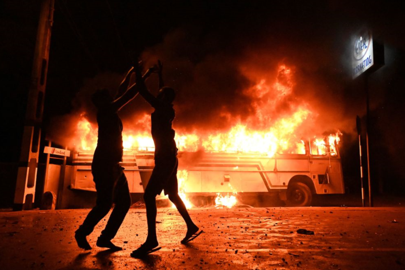 Rioters dance in Colombo's streets as a bus burns outside the president's palace.<i>Photo: Getty</i>