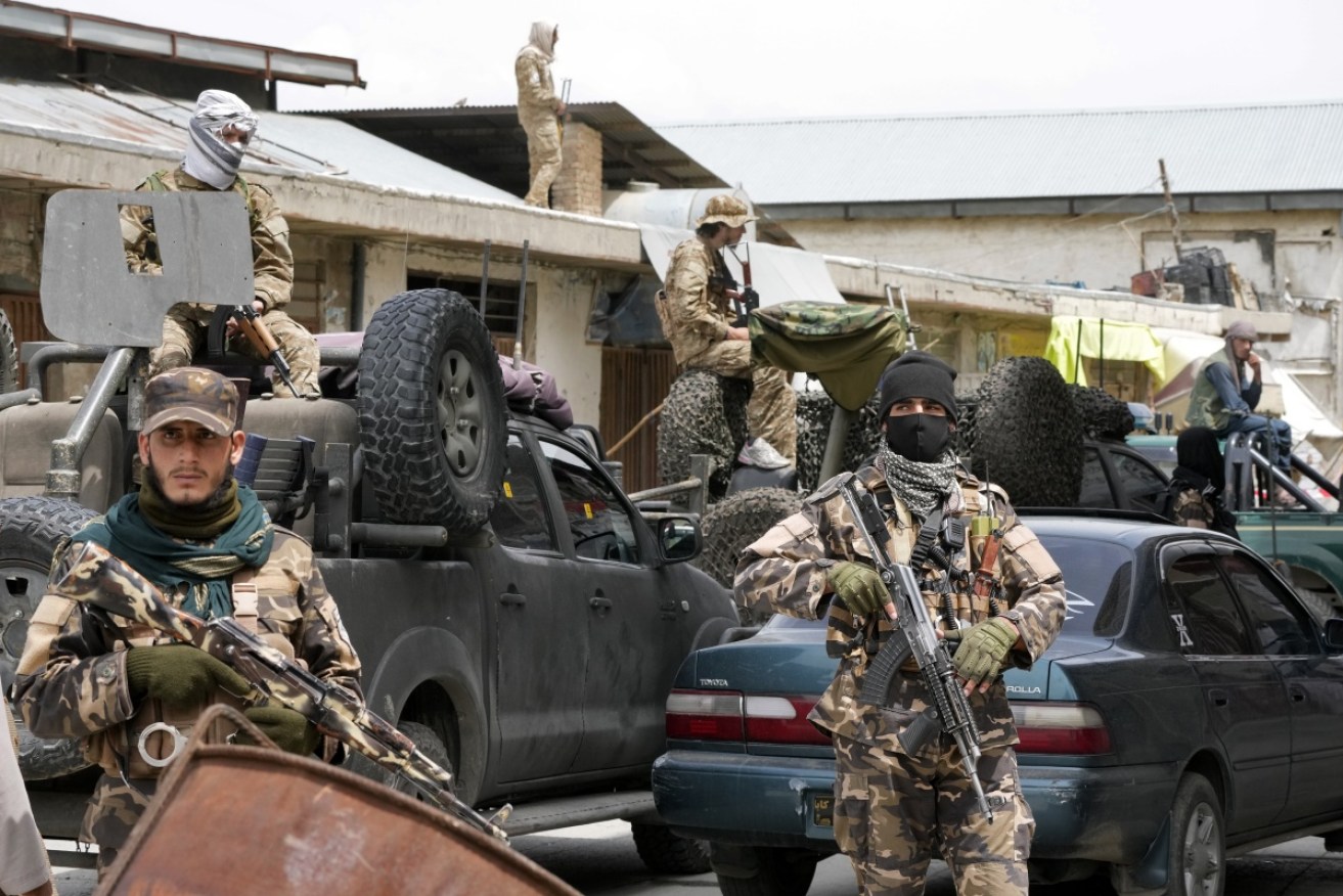 Taliban fighters stand guard at the site of an explosion in Afghanistan.