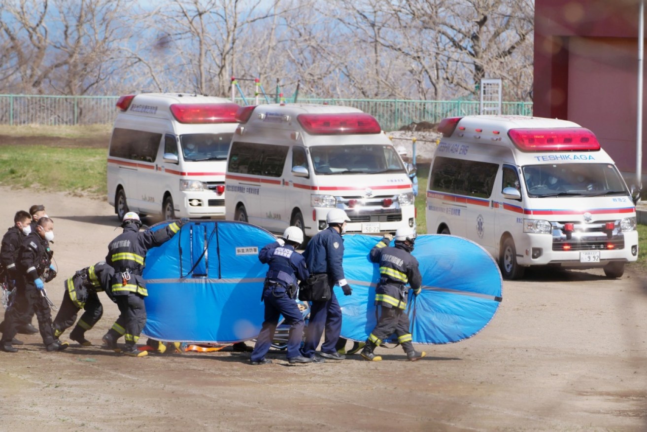 Rescuers transfer a person from the missing Japanese tour boat to a waiting ambulance.