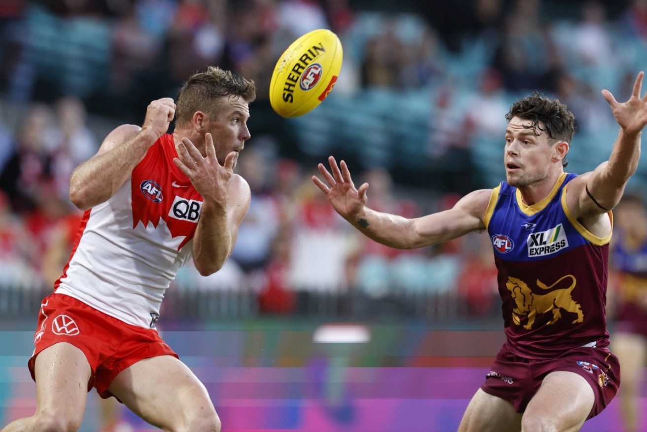 Sydney veteran Luke Parker tries to bypass Brisbane's Lachie Neale with a handball at the SCG.