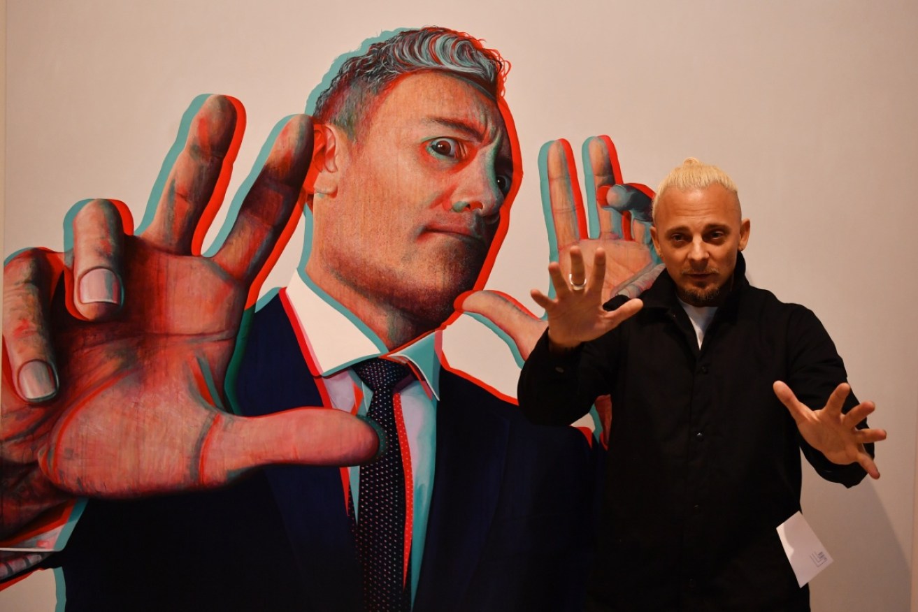 Claus Stangl with his portrait of Oscar-winner Taika Waititi, which has won the Archibald Packing Room Prize.