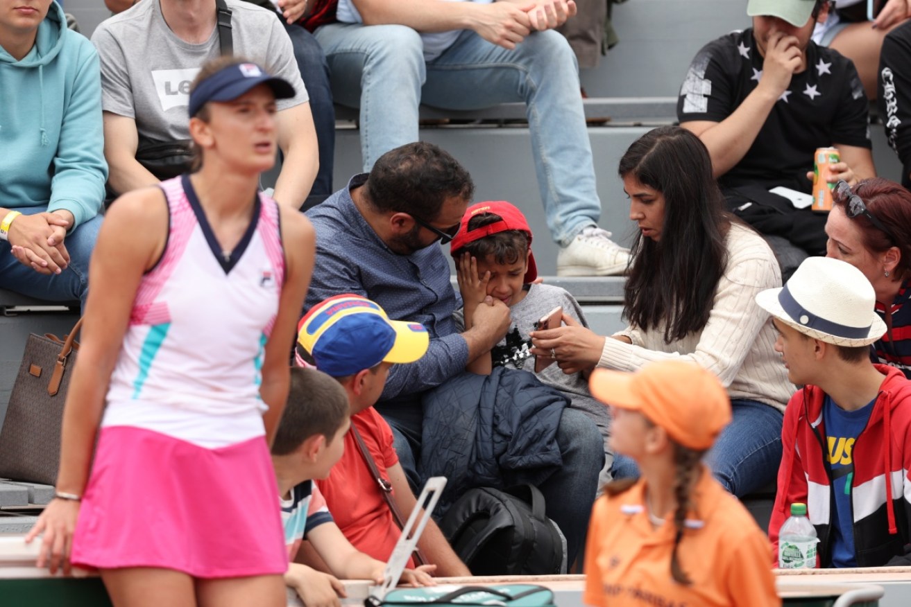 Parents comfort their child after they were struck by Begu's racquet at the French Open.