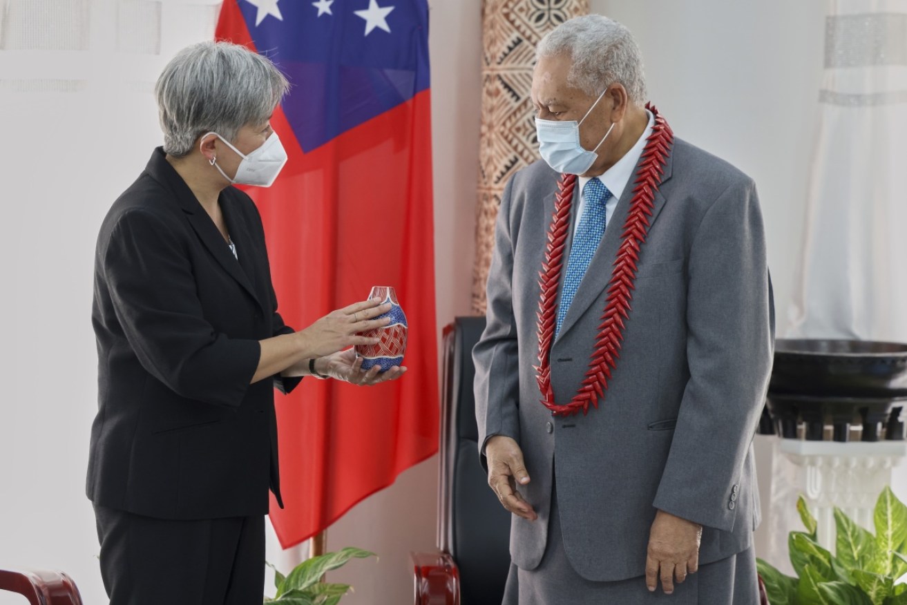 Penny Wong hands a gift to Samoa's president during a diplomatic visit to the Pacific nation.