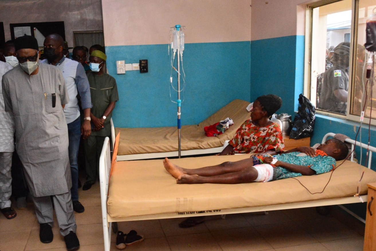 State officials walk past injured victims in hospital after the attack at St Francis Catholic Church in Owo town.