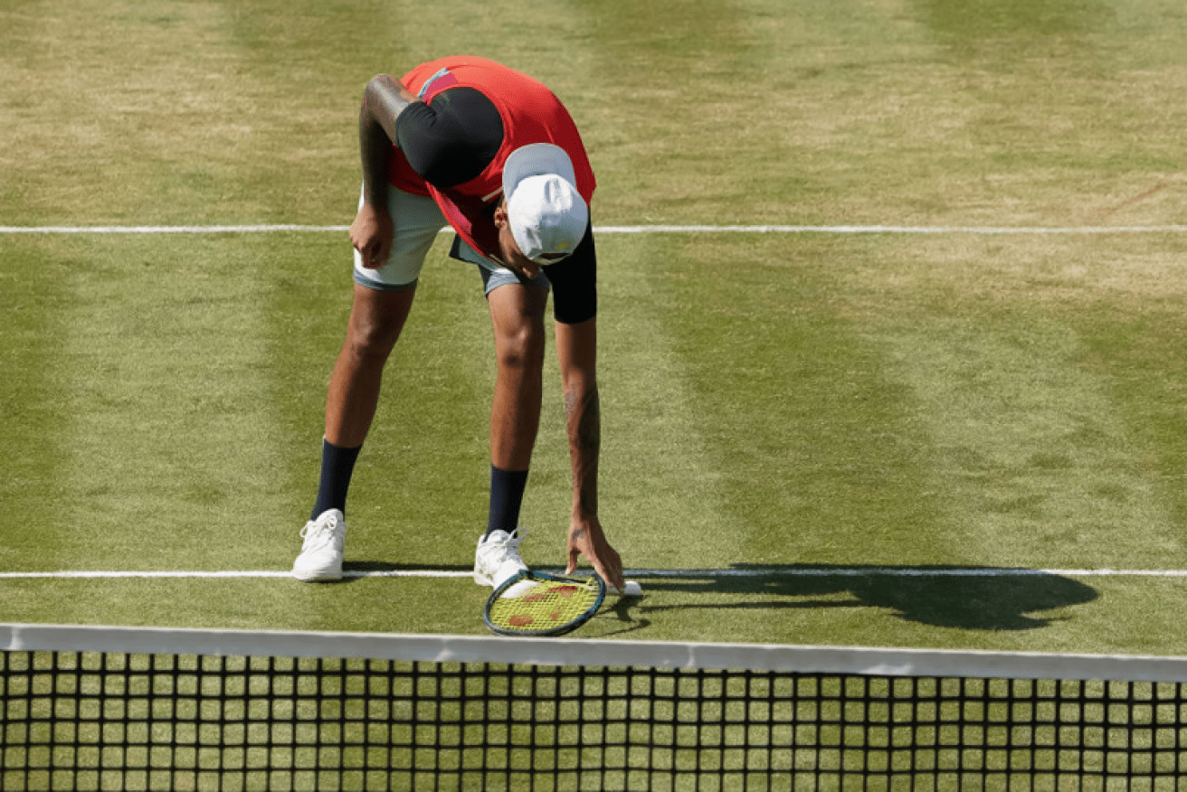 Nick Kyrgios stoops to retrieve the remains of his racquet after blowing his cool once again. <i>Photo: Getty</i>