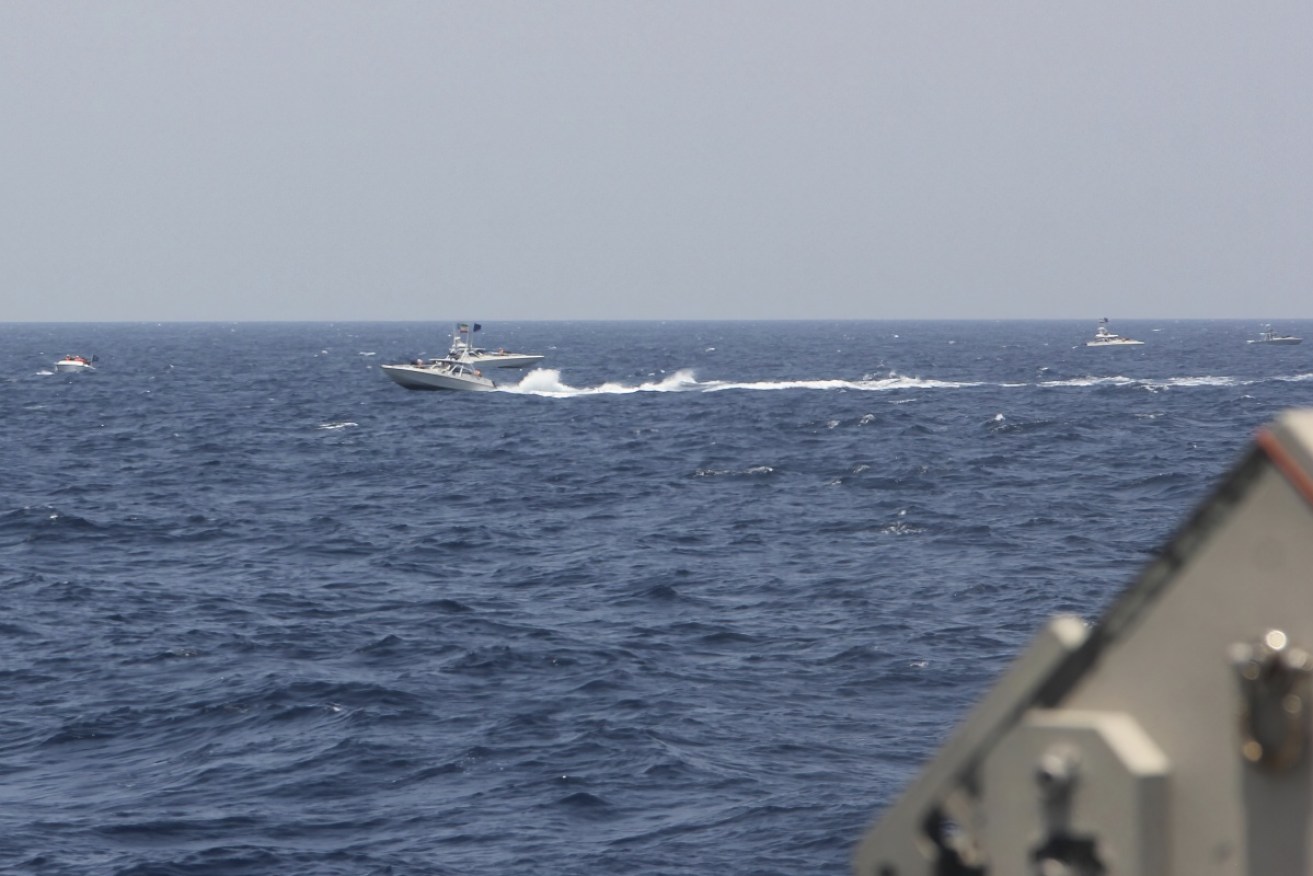 An Iranian attack speedboat passes US naval vessels in the Strait of Hormuz in May 2021.
