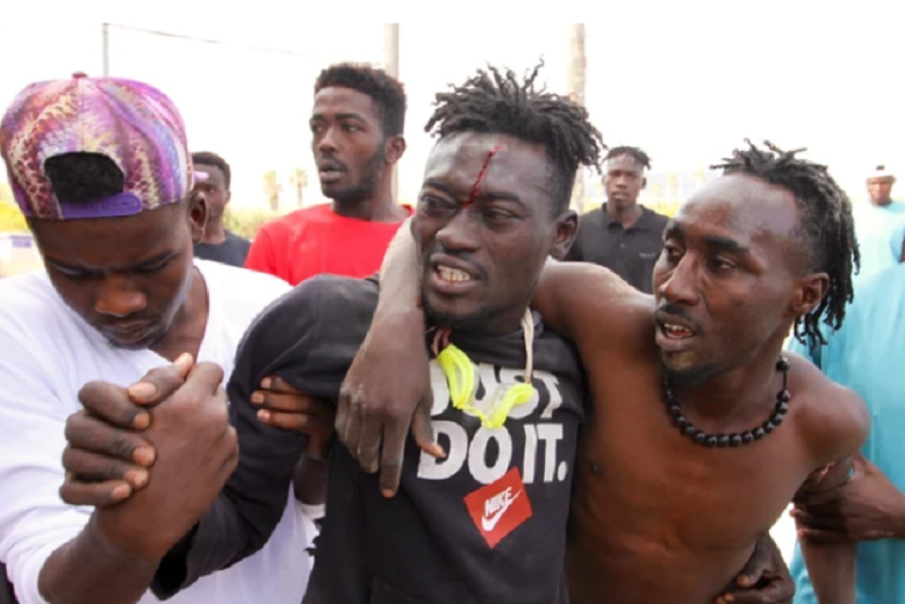 An asylum seeker, blood pouring from a forehead wound, is helped from the melee at the Spanish exclave of Melilla. <i>Photo: Twitter/Lisa Marie</i>