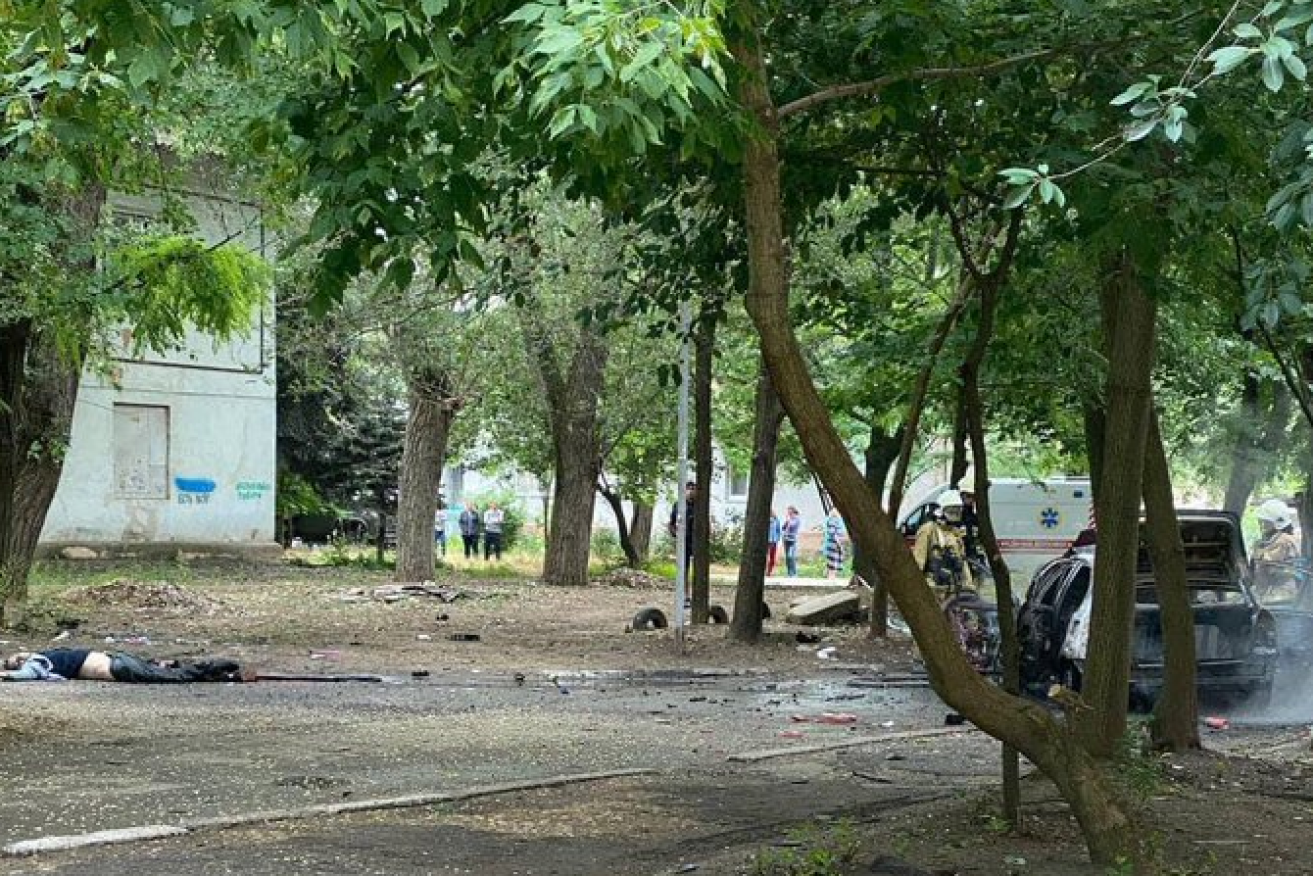 A body (left) lies amid the debris of Russian collaborator Dmitry Savluchenko's shattered car. <i>Photo: Michael Elgort/Twitter</i>