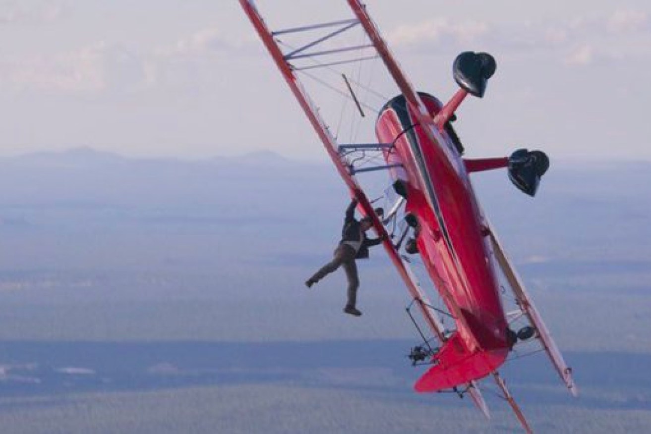 Tom cruise dangles from a plane.