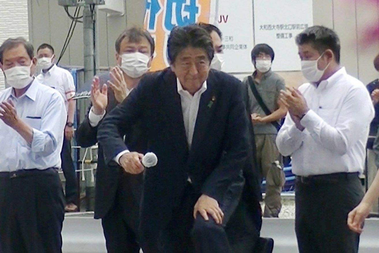 This photo catches assassin Tetsuya Yamagami, in the grey T-shirt, closing in on Abe seconds before the fatal shot.  <i>Photo: AAP</i>