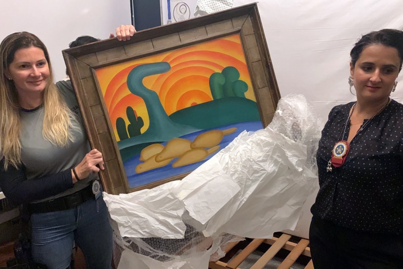 Officers show artist Tarsila do Amaral's painting titled "Sol Poente" after it was seized during a police operation in Rio de Janeiro, Brazil.