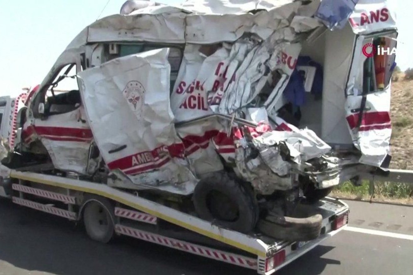 A crumpled ambulance vehicle is taken away. 