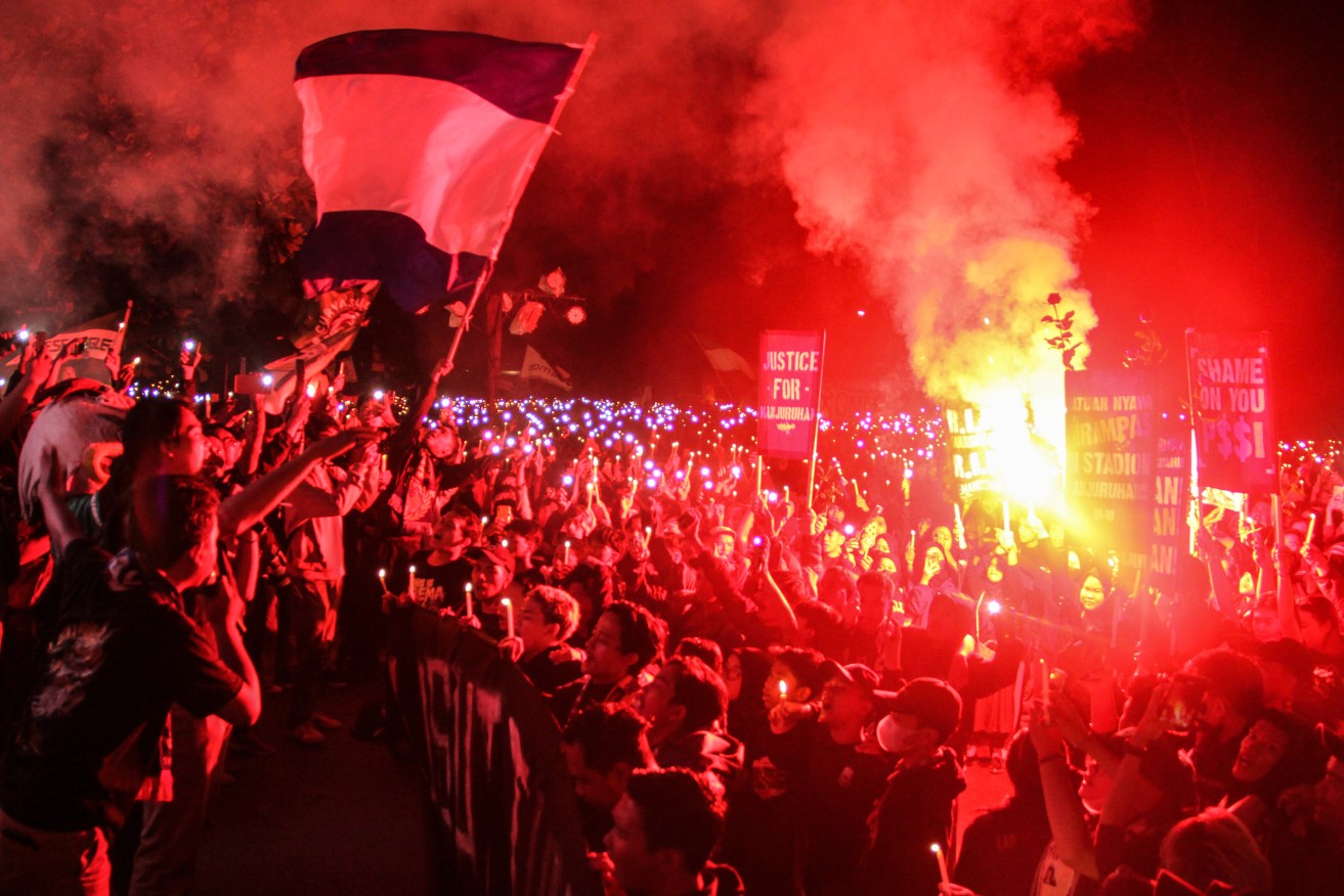 Soccer fans light flares as they chant slogans during a candle light vigil for the victims of Saturday's soccer stampede, in Sleman, Indonesia 