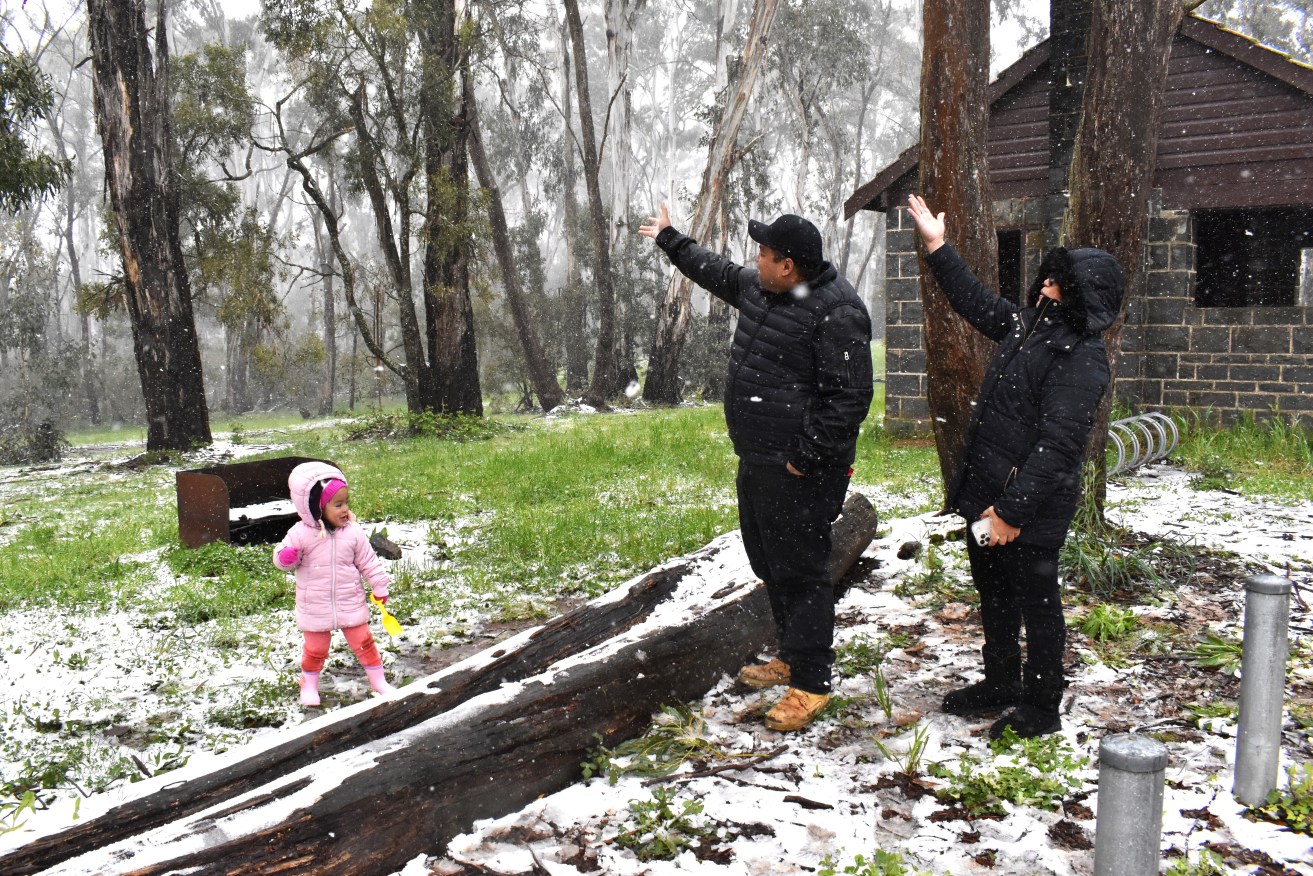 Orange locals Jake and Sherlin Galicia with their daughter Sofia in a snow flurry at the Pinnacle Reserve near Orange.