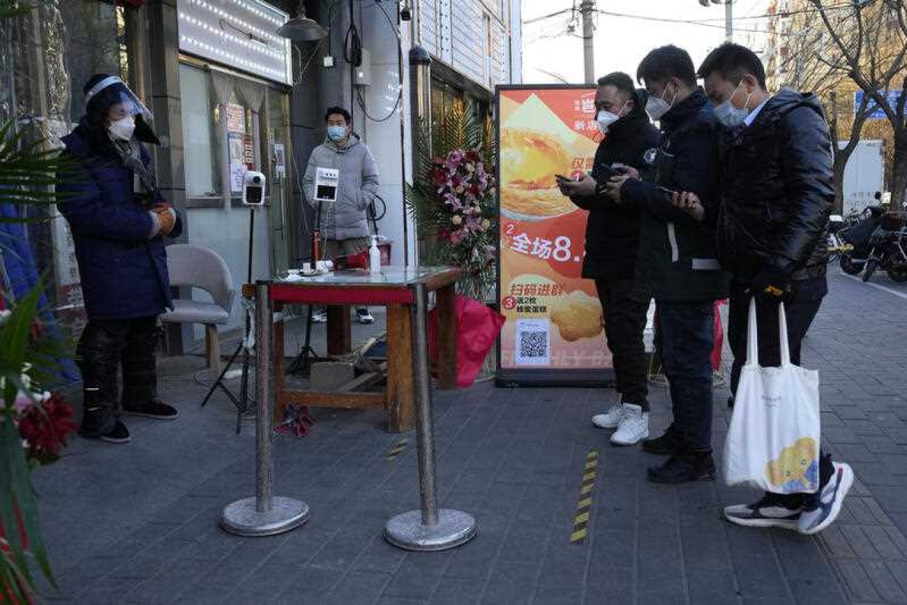 Residents show their health code before they enter a market as restrictions ease in Beijing.
