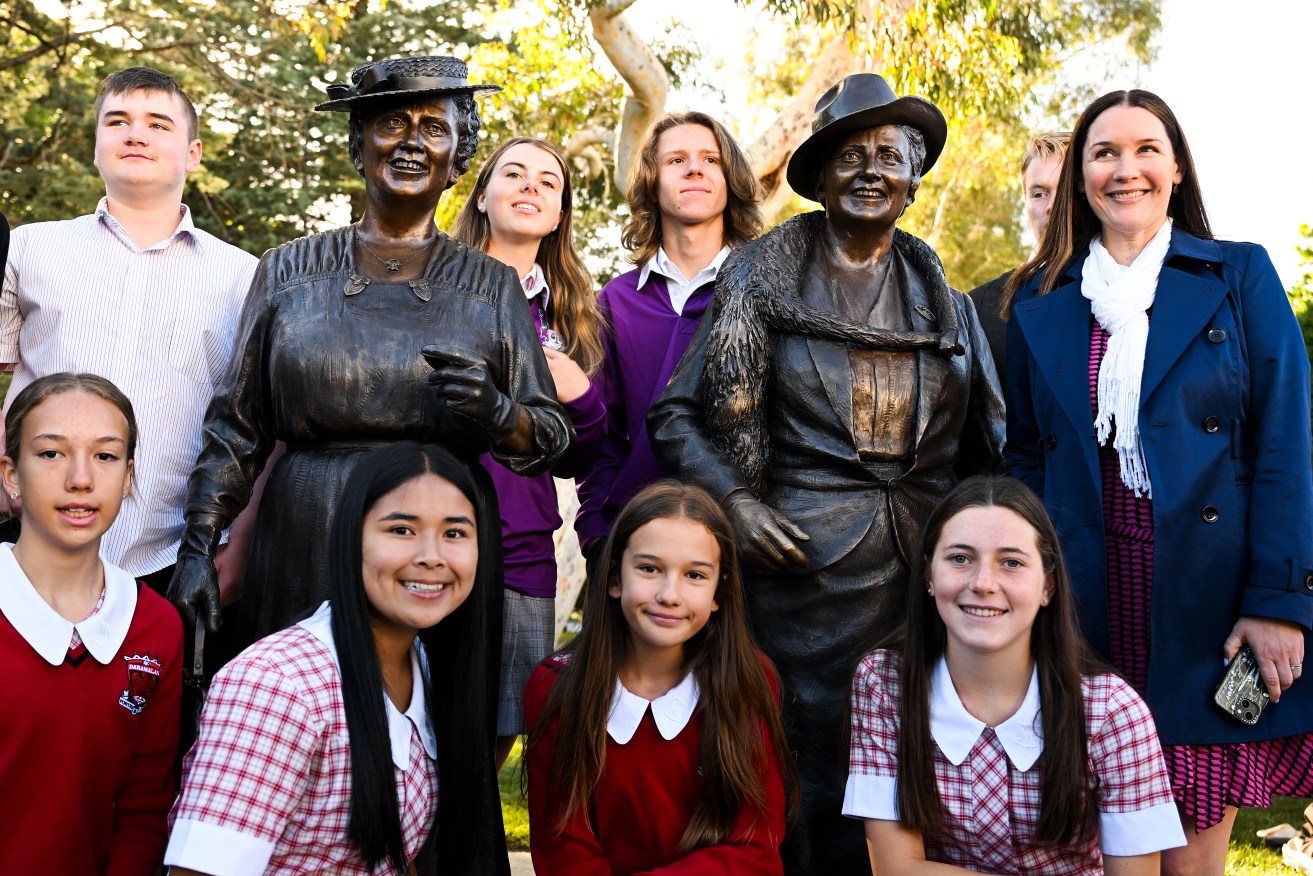 Students pose for photographs next to the statues of Australia's first women federal parliamentarians Dame Enid Lyons and Dame Dorothy Tangney, unveiled in Canberra on Wednesday.