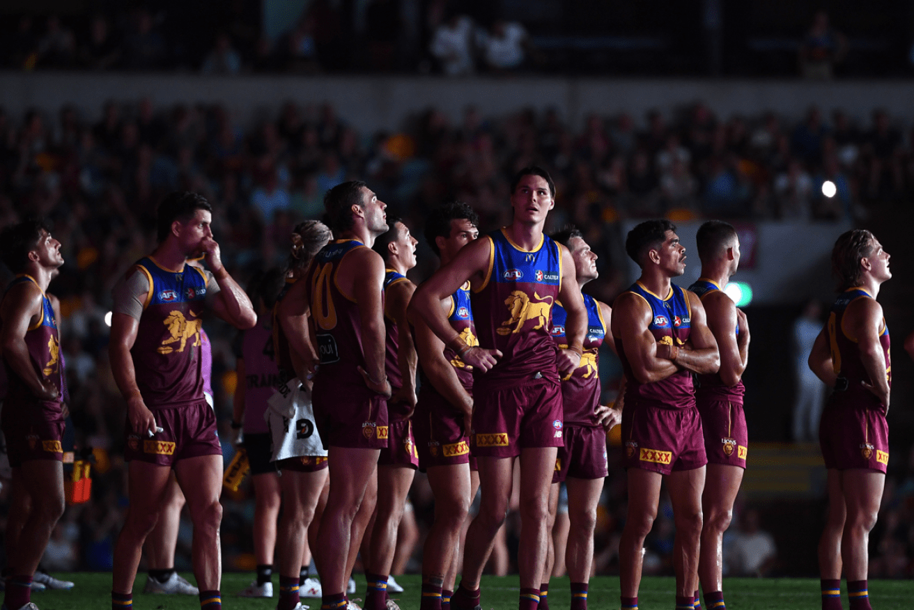 Baffled Brisbane Lions players gather in the semi-darkness after the Gabba's light towers went dark. <i>Photo: AAP</i>
