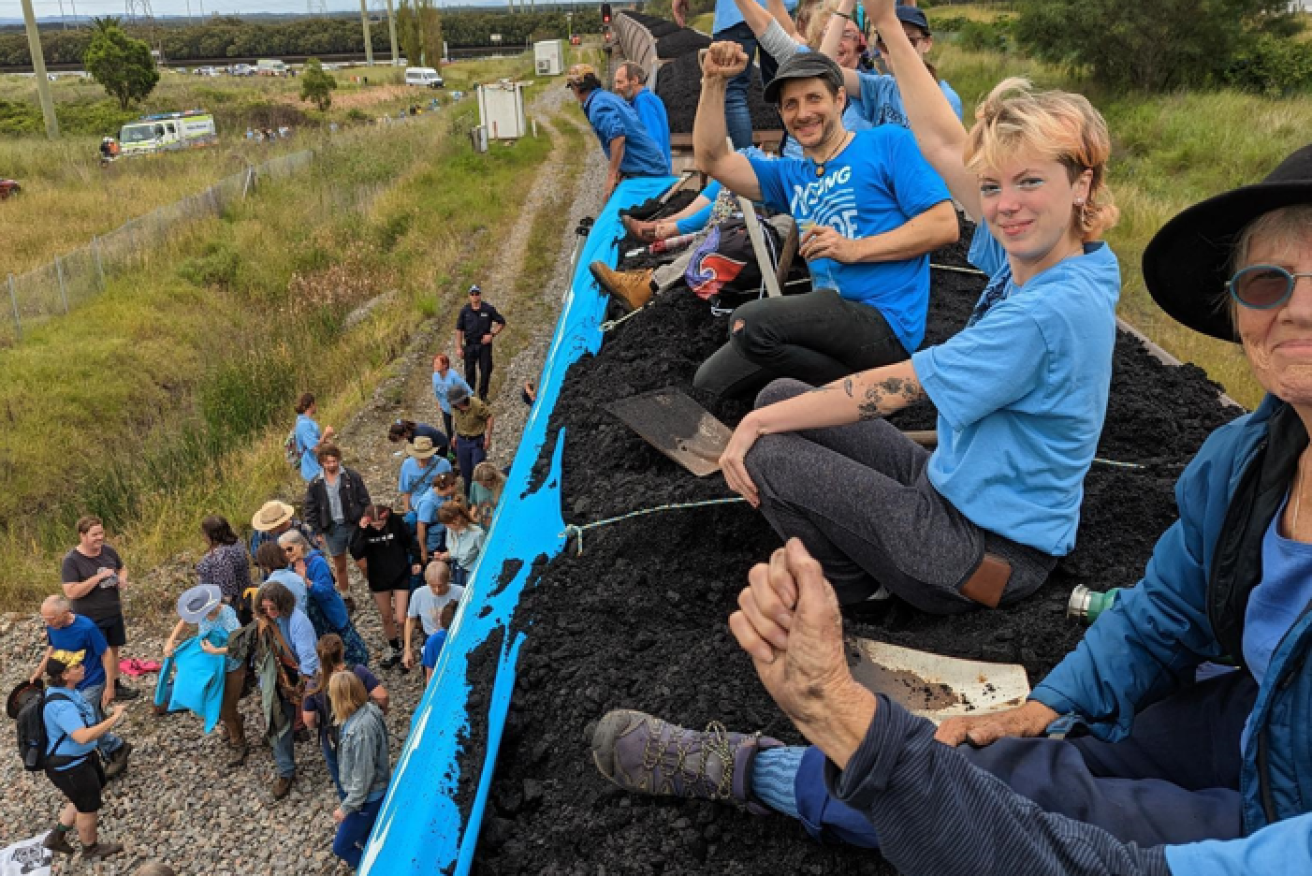Climate campaigners raise their fists in defiance after stopping the train and its cargo. <i>Photo: AAP</i>