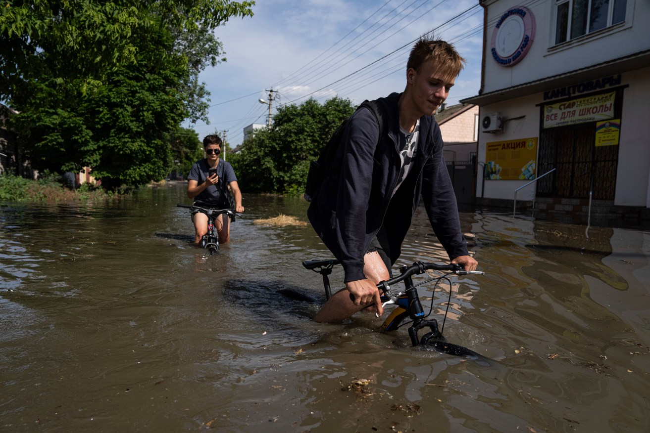 Kherson residents try to flee the rising floodwaters on bikes.
